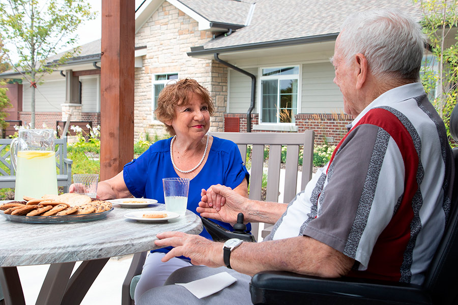 A couple enjoys cookies on a patio.