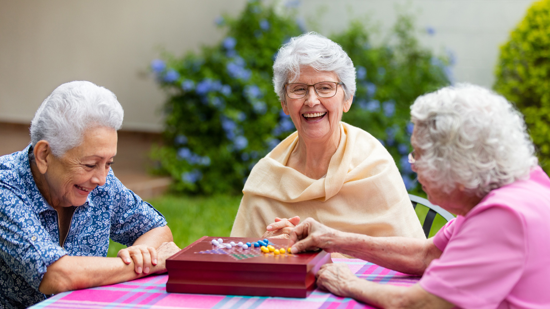 A smiling group of women playing Chinese Checkers.